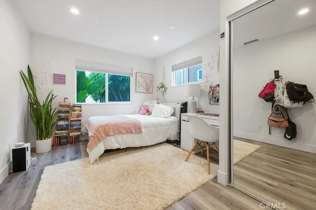 a bedroom with a bed table flowerpot and window