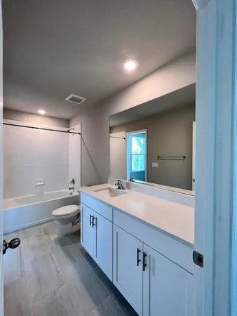 a bathroom with a granite countertop sink mirror bathtub and toilet