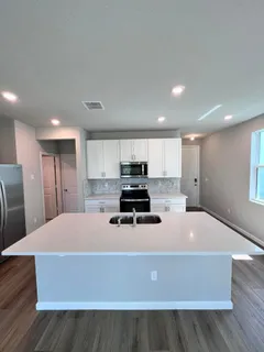 a kitchen with stainless steel appliances a stove top oven a sink with wooden floors