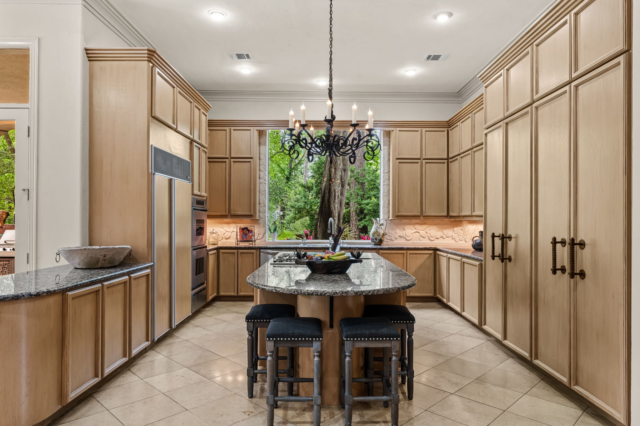 6 Mott Lane Houston, TX 77024 - Photo 28 of 50 Chef's kitchen with extensive custom cabinetry, granite countertops and a spacious center island with seating. High0end appliances, abundant storage, and a picturesque window overlooking lush greenery make this space both functional and beautfully inviting.