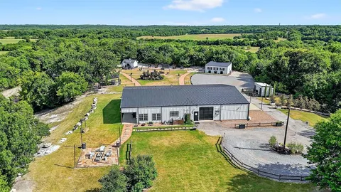 an aerial view of a residential houses with outdoor space and trees all around