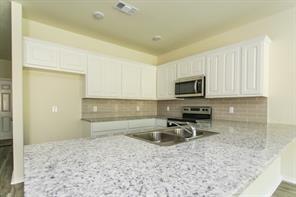 690 Union Street, Unit 1 Bonham, TX 75418 - Photo 2 of 15 Kitchen with white cabinets, tasteful backsplash, a peninsula, and stainless steel appliances