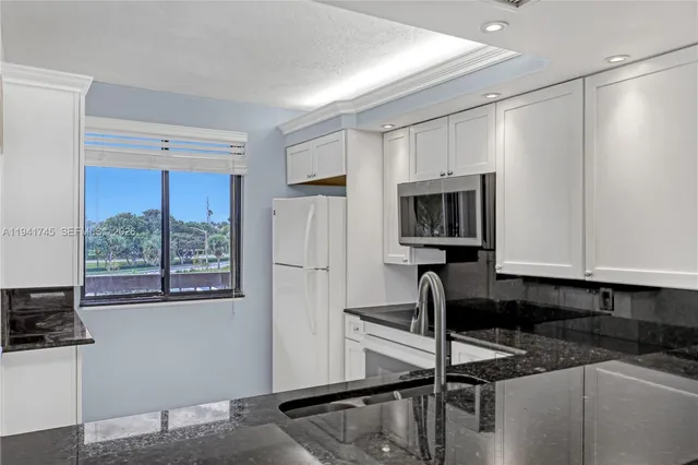 a kitchen with granite countertop a stove a sink and a refrigerator