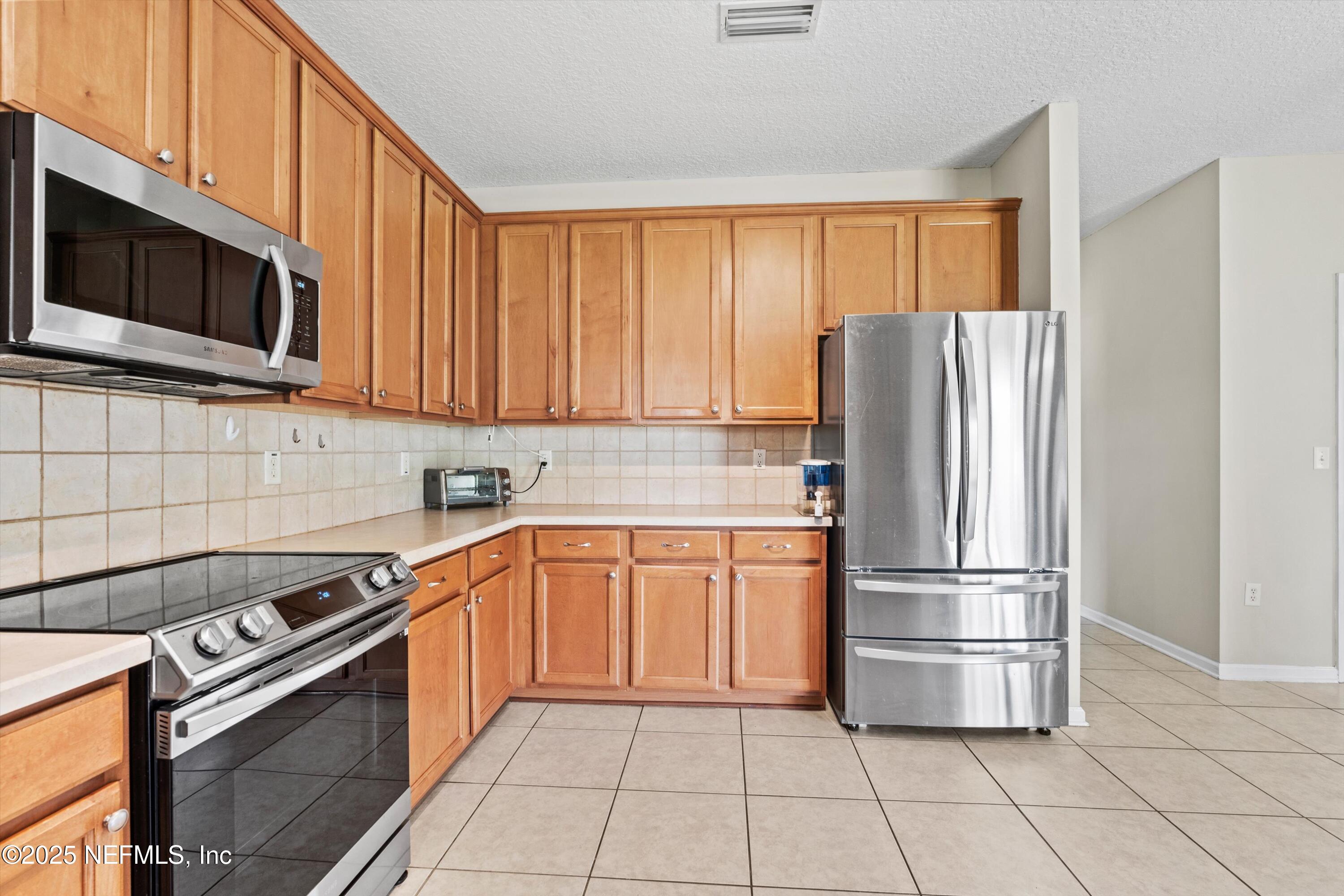 2360 Golfview Drive Fleming Island, FL 32003 - Photo 35 of 60 a kitchen with stainless steel appliances granite countertop a refrigerator stove and microwave