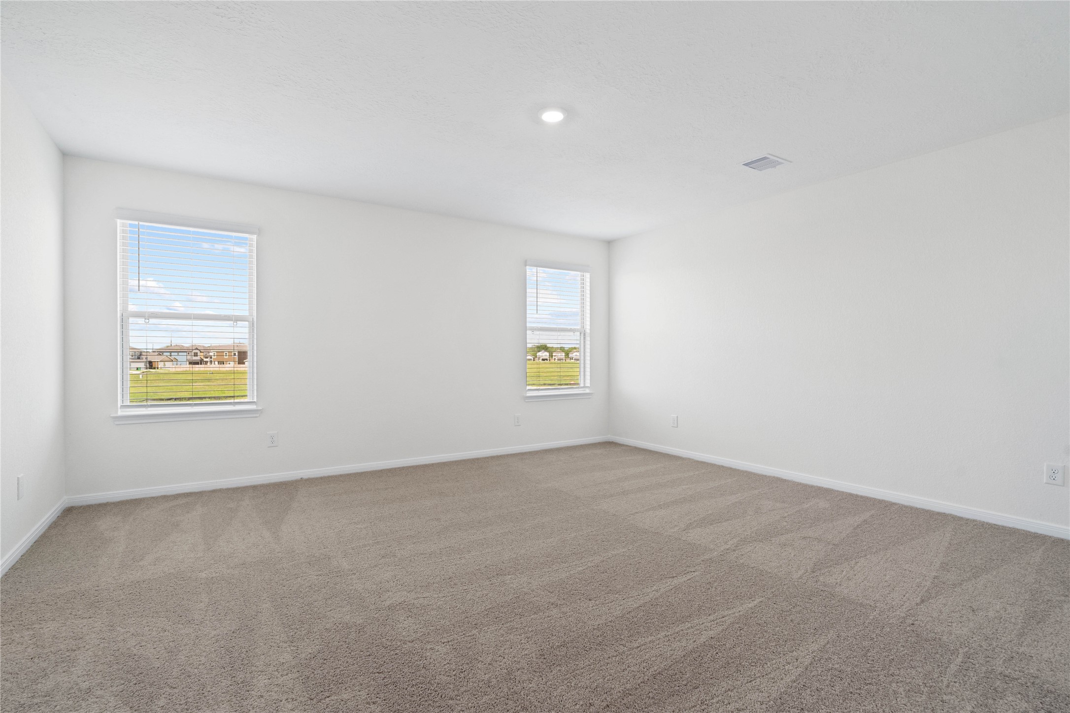 6418 Kentfield Drive Rosharon, TX 77583 - Photo 12 of 23 Unwind after a long day in this stunning primary suite! This spacious retreat features plush carpeting, warm-toned walls, high ceilings, recessed lighting, and large windows with privacy blinds for comfort and tranquility.