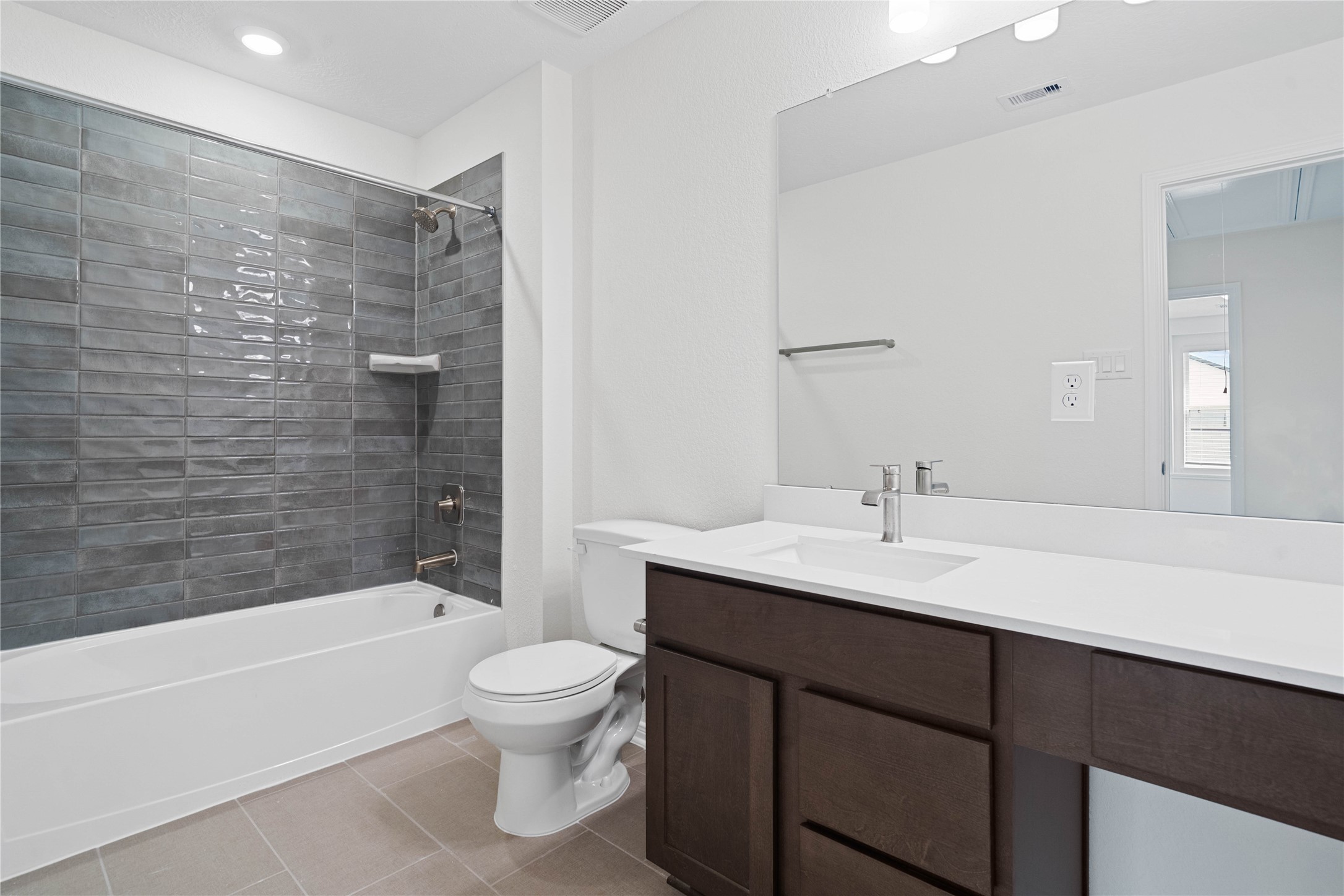 6418 Kentfield Drive Rosharon, TX 77583 - Photo 17 of 23 The secondary bathroom showcases tile flooring, a bath/shower combo with a Daltile Mesmerist Charm tile surround, an extended cabinet with knee space and stunning light countertop, a stylish mirror, sleek fixtures, and contemporary finishes throughout.