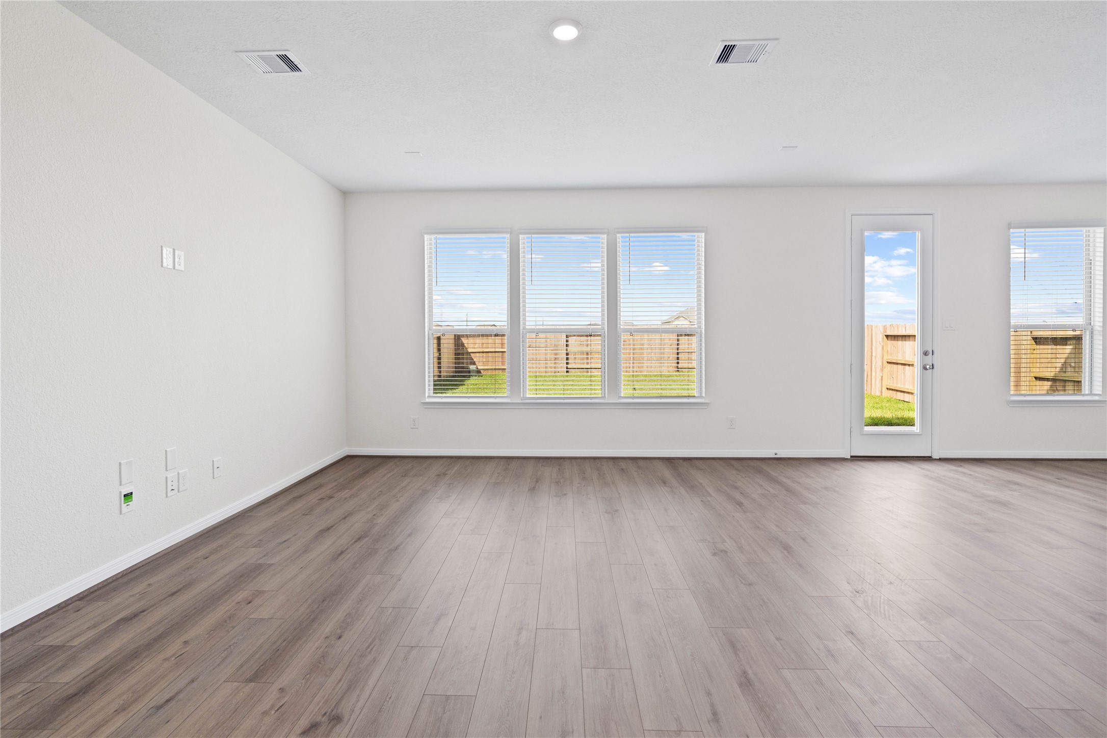 6418 Kentfield Drive Rosharon, TX 77583 - Photo 5 of 23 This bright and airy Great Room offers a spacious layout ideal for both relaxing evenings and lively gatherings. Designed for comfort and connection, it features Layton Lake vinyl plank flooring in Wild Dunes, large windows with blinds, high ceilings, recessed lighting, and seamless access to the stunning kitchen and dining—perfect for everyday living and entertaining alike.