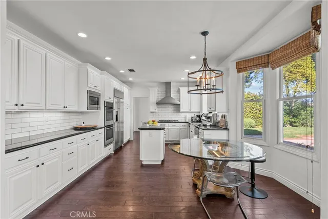 a kitchen with kitchen island granite countertop a sink appliances a counter space and wooden floor