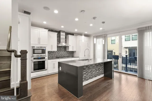 a kitchen with stainless steel appliances granite countertop a refrigerator a oven and white cabinets with wooden floor