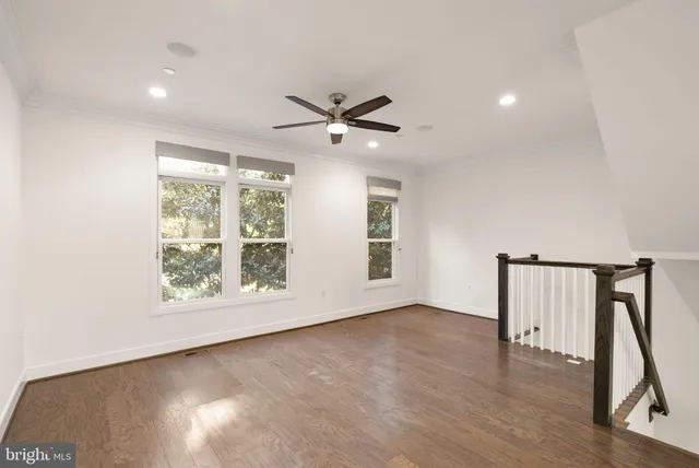 a view of an empty room with wooden floor and stairs