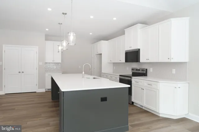 a large kitchen with kitchen island a sink wooden floor and a large window