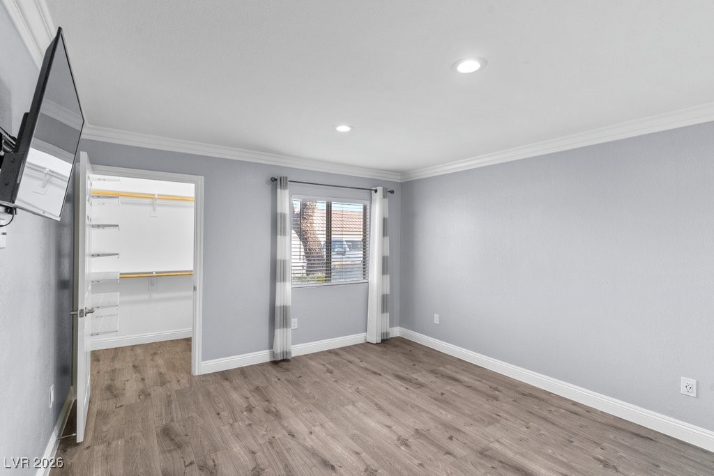 7885 West Flamingo Road, Unit 1053 Las Vegas, NV 89147 - Photo 12 of 33 Unfurnished bedroom with ornamental molding, a spacious closet, light wood-style flooring, and recessed lighting