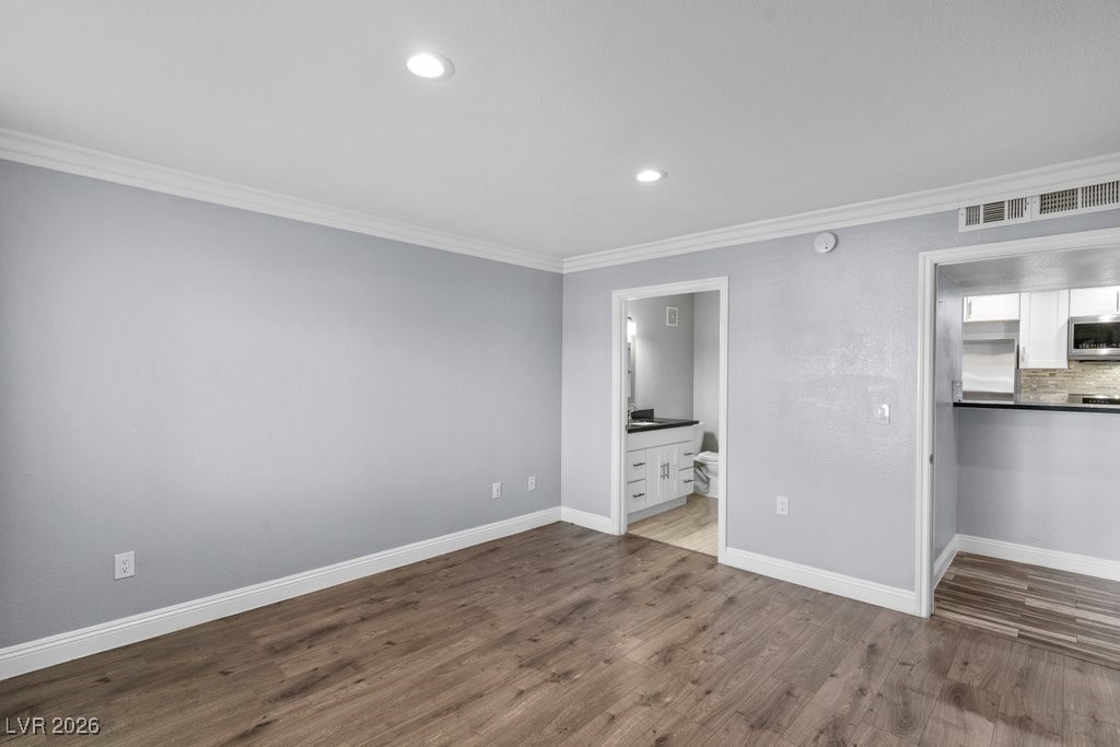 7885 West Flamingo Road, Unit 1053 Las Vegas, NV 89147 - Photo 13 of 33 Unfurnished bedroom featuring crown molding, recessed lighting, dark wood finished floors, ensuite bath, and stainless steel fridge