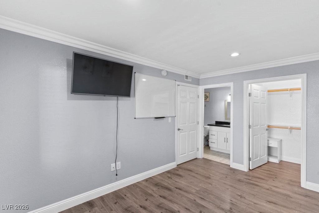 7885 West Flamingo Road, Unit 1053 Las Vegas, NV 89147 - Photo 20 of 33 Unfurnished bedroom with ornamental molding, a walk in closet, wood finished floors, recessed lighting, and connected bathroom