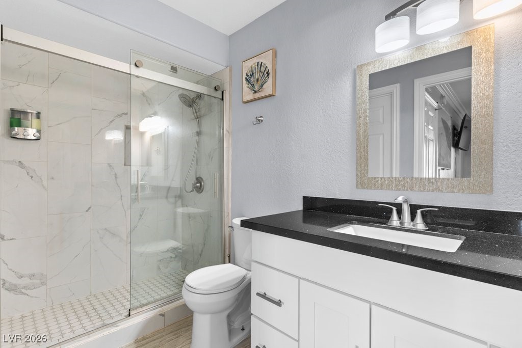 7885 West Flamingo Road, Unit 1053 Las Vegas, NV 89147 - Photo 22 of 33 Full bath with vanity, a marble finish shower, and a textured wall