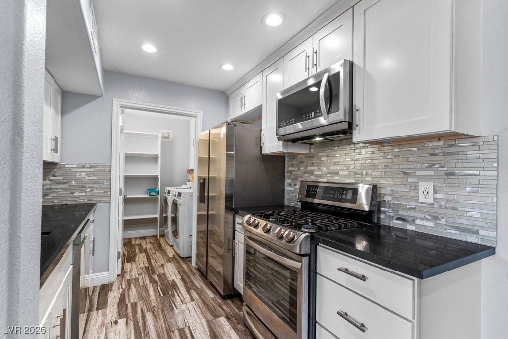 7885 West Flamingo Road, Unit 1053 Las Vegas, NV 89147 - Photo 3 of 33 Kitchen with stainless steel appliances, separate washer and dryer, white cabinetry, dark wood-style floors, and recessed lighting