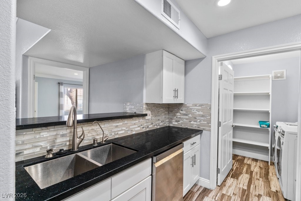 7885 West Flamingo Road, Unit 1053 Las Vegas, NV 89147 - Photo 4 of 33 Kitchen with white cabinetry, dishwasher, dark stone countertops, backsplash, and light wood-style flooring