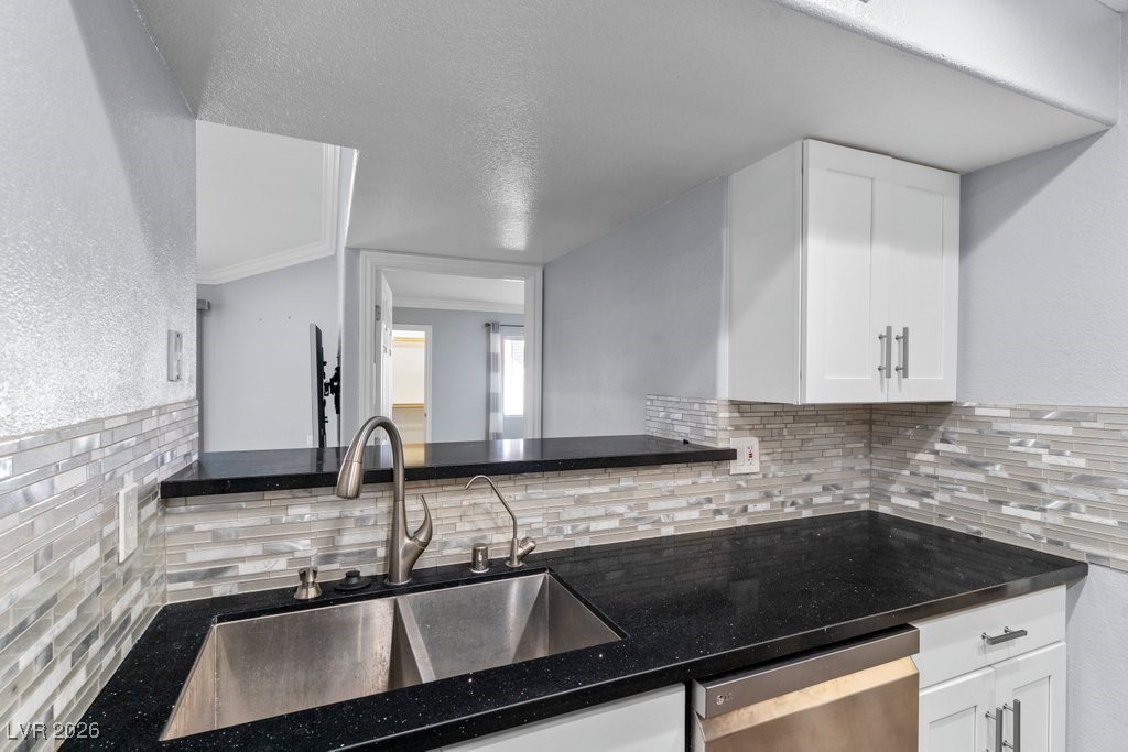 7885 West Flamingo Road, Unit 1053 Las Vegas, NV 89147 - Photo 5 of 33 Kitchen with a textured wall, white cabinets, stainless steel dishwasher, a textured ceiling, and dark stone counters