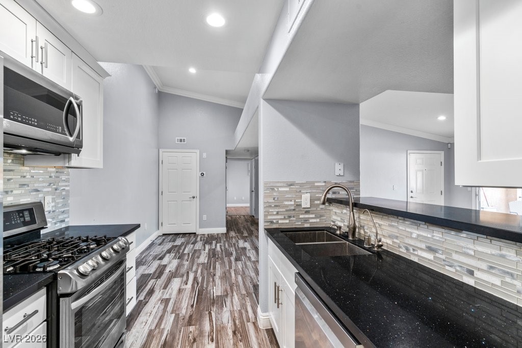 7885 West Flamingo Road, Unit 1053 Las Vegas, NV 89147 - Photo 6 of 33 Kitchen featuring decorative backsplash, stainless steel appliances, white cabinetry, dark stone counters, and crown molding