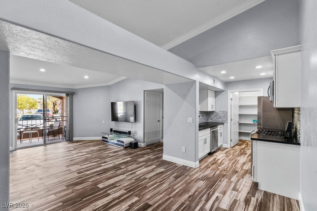 7885 West Flamingo Road, Unit 1053 Las Vegas, NV 89147 - Photo 33 of 33 Kitchen featuring white cabinets, ornamental molding, open floor plan, light wood finished floors, and recessed lighting