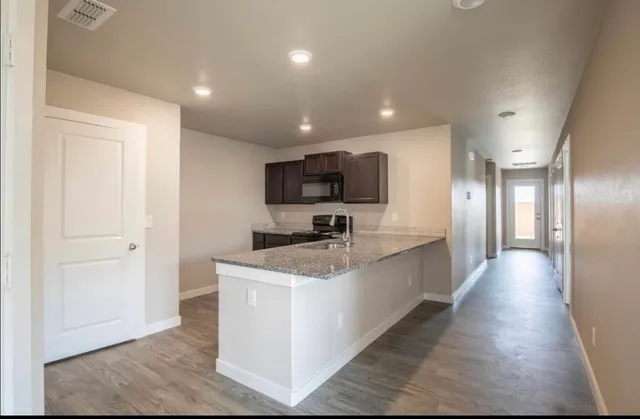 a large kitchen with stainless steel appliances granite countertop a sink a stove top oven a counter space and cabinets