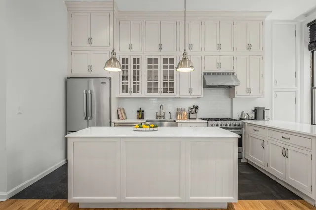 a kitchen with stainless steel appliances granite countertop a sink a stove and white cabinets