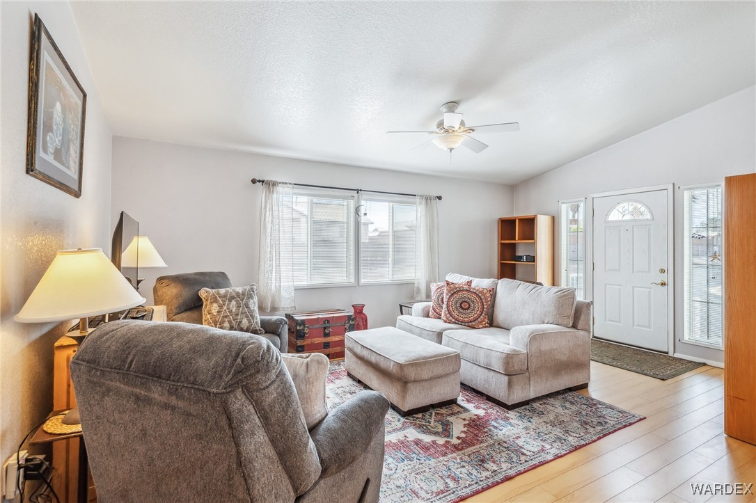 Living area featuring lofted ceiling, light wood-style flooring, and a ceiling fan