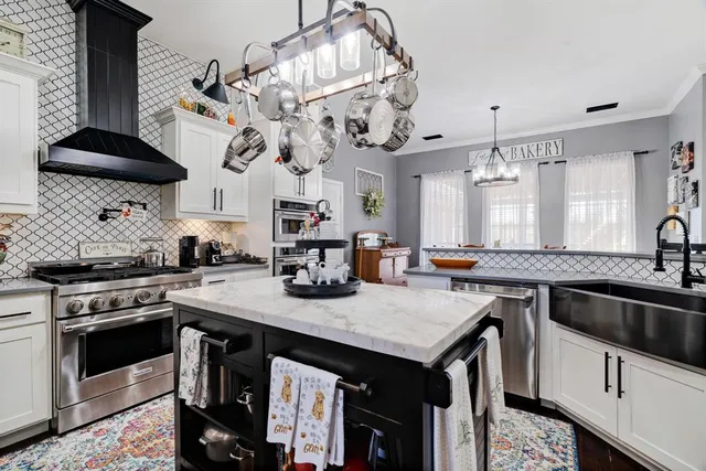 a kitchen with granite countertop a sink a stove and chairs