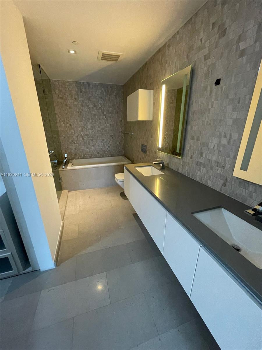 88 Southwest 7th Street, Unit 1608 Miami, FL 33130 - Photo 9 of 14 a bathroom with a granite countertop sink a toilet a mirror and bathtub