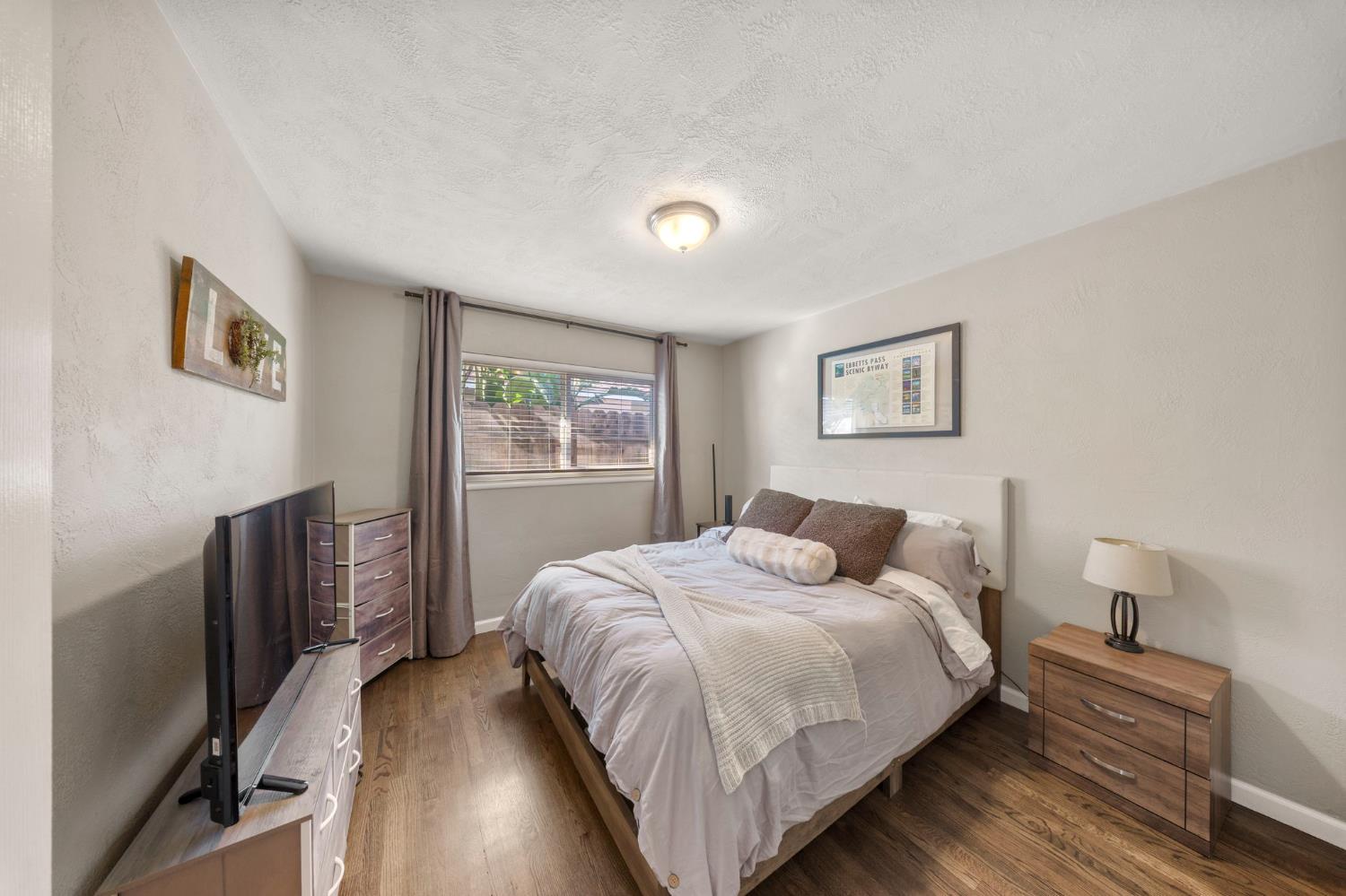 1405 Fordham Avenue Modesto, CA 95350 - Photo 21 of 32 a bedroom with a bed and a flat tv screen on a dresser