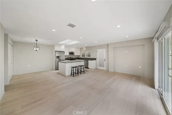 a view of kitchen with stainless steel appliances granite countertop cabinets a sink and a wooden floor