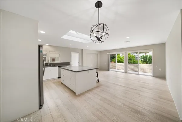 a kitchen with stainless steel appliances granite countertop a refrigerator a sink dishwasher a s stove top oven a large island with white cabinets and wooden floor