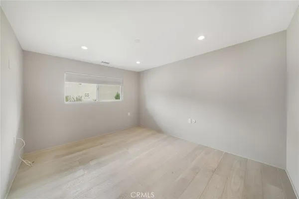 a view of empty room with wooden floor and kitchen