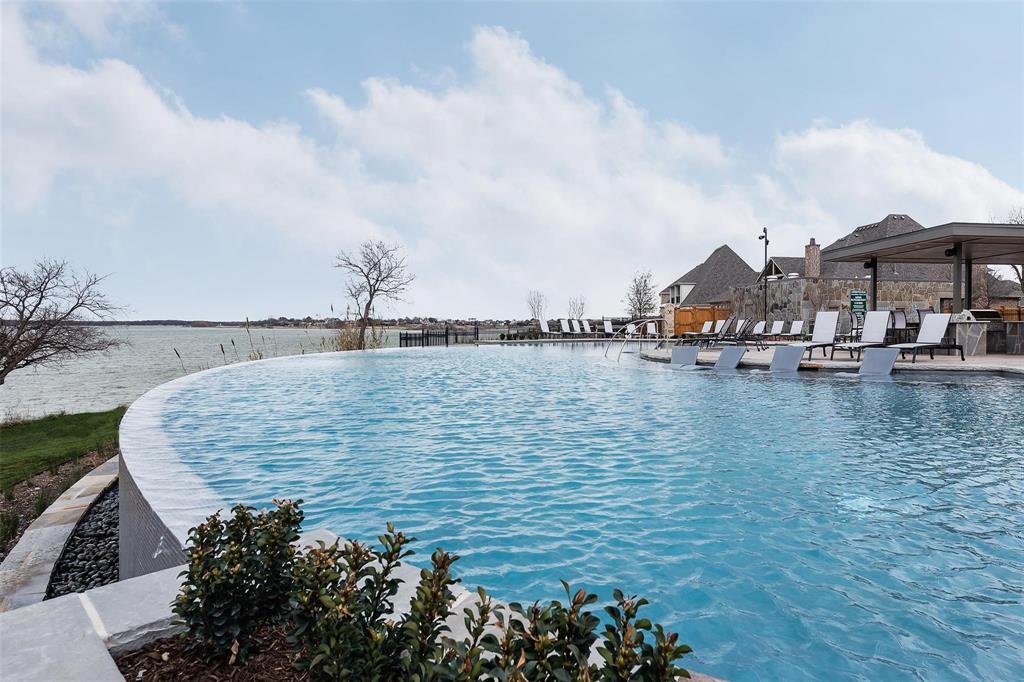 8440 Colburn The Colony, TX 75056 - Photo 27 of 34 Enjoy breathtaking lake views from the resort-style infinity-edge neighborhood pool, one of The Tribute’s most sought-after amenities. Overlooking the shoreline, this stunning retreat features tanning ledges, abundant lounge seating, covered gathering spaces, and a true vacation-like atmosphere perfect for relaxing, socializing, and soaking in the lakeside lifestyle.