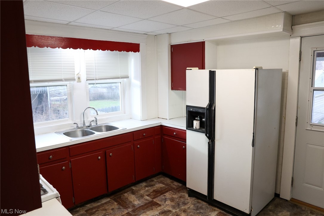 1309 Krumroy Road Akron, OH 44306 - Photo 13 of 30 Kitchen featuring white fridge with ice dispenser, a drop ceiling, dark tile flooring, and sink