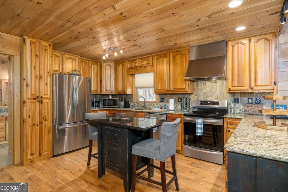 165 Christian Crossing, Unit 15 Morganton, GA 30560 - Photo 28 of 58 a kitchen with granite countertop kitchen island stainless steel appliances a refrigerator a sink a stove and cabinets