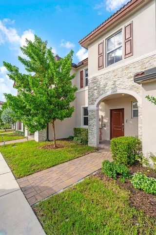a front view of a house with a garden and trees