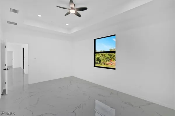 en empty room with a window and a ceiling fan