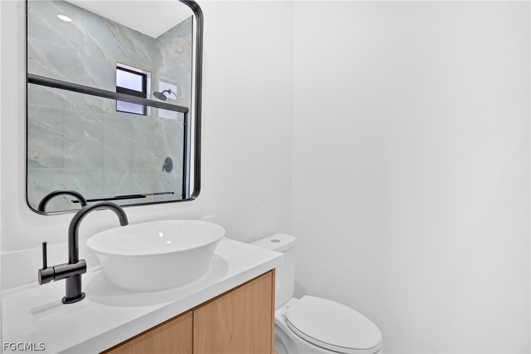 5231 6th Street West Lehigh Acres, FL 33971 - Photo 10 of 26 a bathroom with a sink a toilet and a mirror