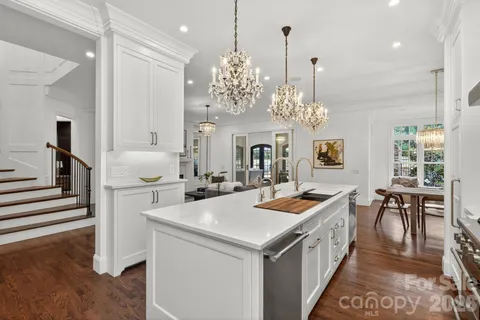 a kitchen that has a lot of white cabinets and stainless steel appliances