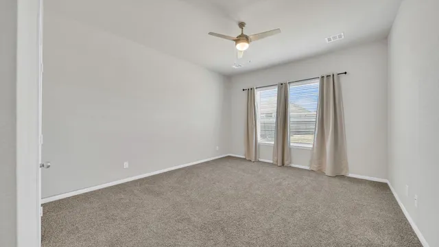 an empty room with windows and chandelier fan