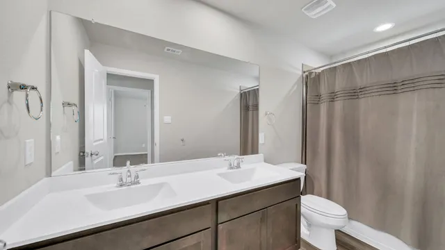 a bathroom with a double vanity sink toilet and a mirror