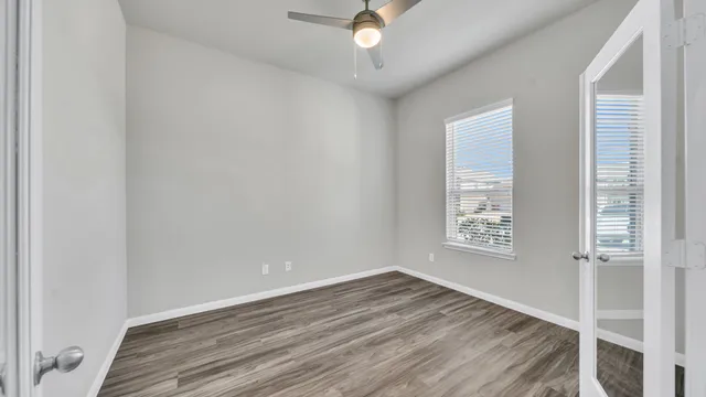 a view of an empty room with wooden floor and a window