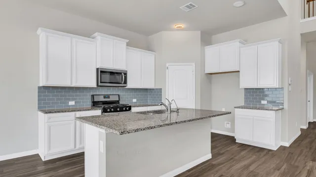 a kitchen with granite countertop white cabinets stove a sink and dishwasher with wooden floor
