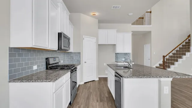 a kitchen with stainless steel appliances granite countertop a sink stove and cabinets