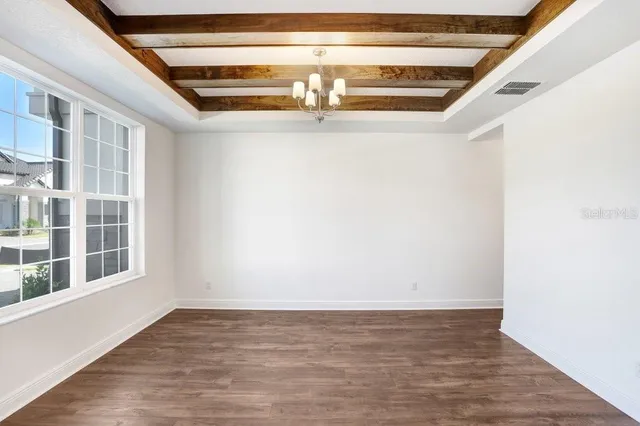 a view of an empty room with wooden floor and windows
