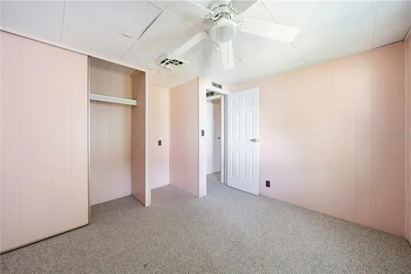an empty room with a ceiling fan and a window
