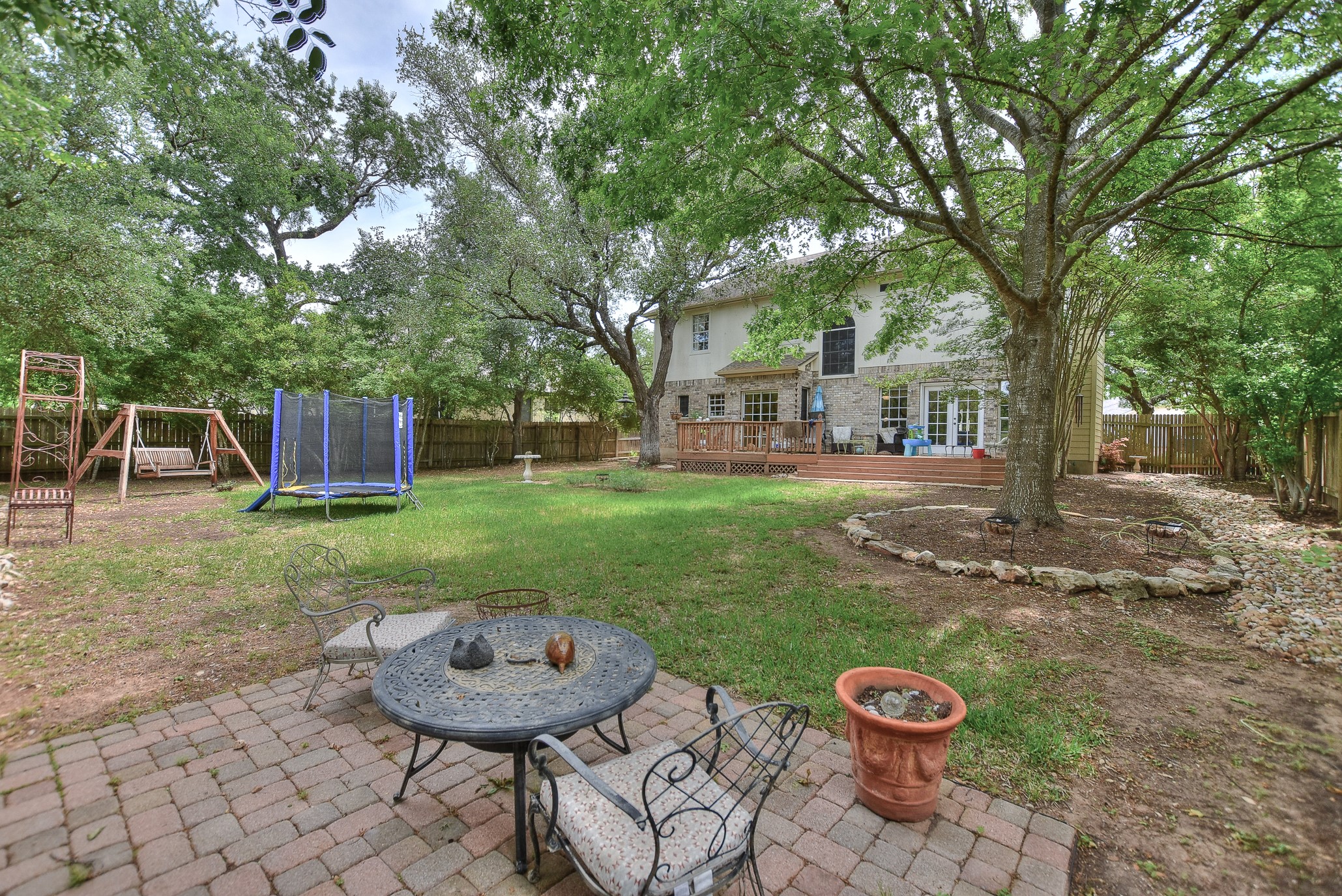 1609 Colton Way Cedar Park, TX 78613 - Photo 19 of 24 An inviting outdoor patio leads to a sprawling lawn, shaded by mature trees, and a spacious wooden deck behind the home.
