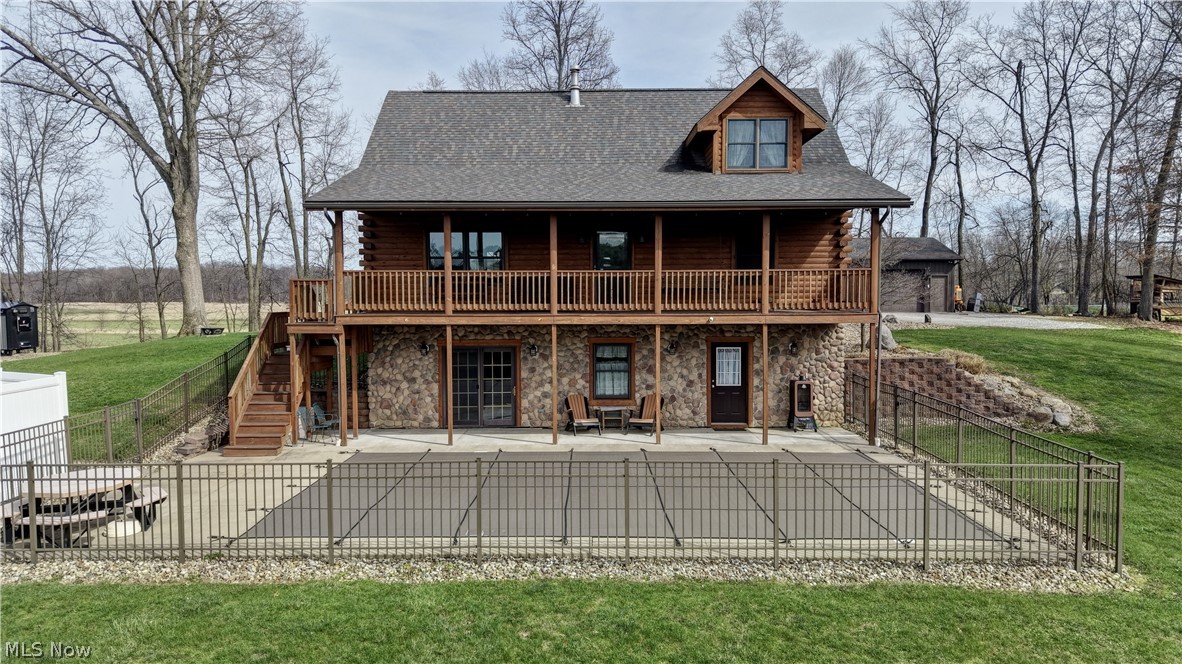 8045 McFadden Road Shreve, OH 44676 - Photo 8 of 45 Rear view of house with log siding, a fenced backyard, stone siding, and roof with shingles
