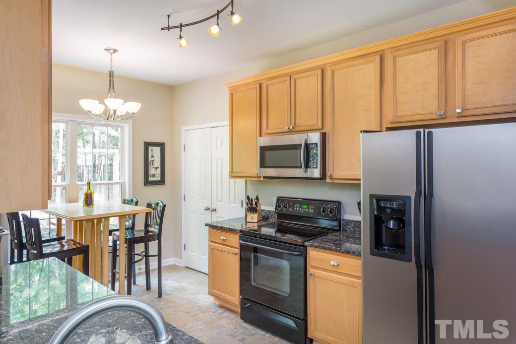 5206 Groveside Court Raleigh, NC 27613 - Photo 4 of 12 a kitchen with stainless steel appliances granite countertop a stove top oven a sink dishwasher a dining table and chairs with wooden floor